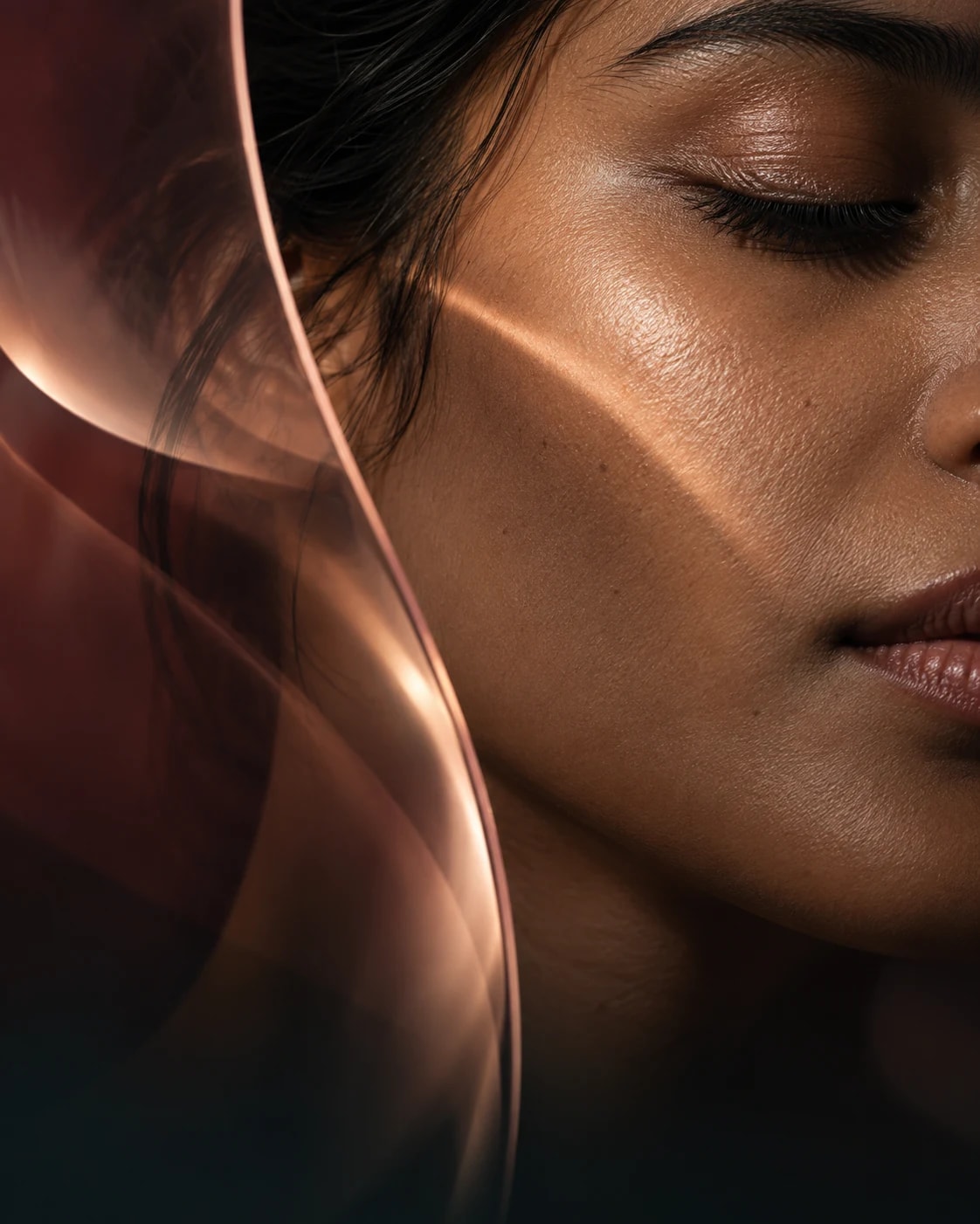 Editorial close-up of natural skin texture framed by blush glass and warm light